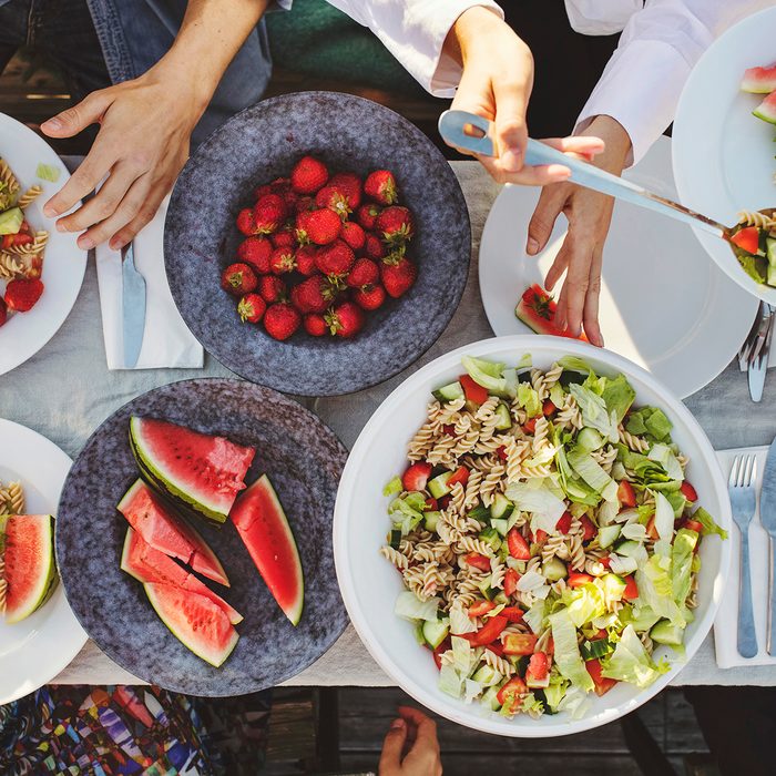 Directly Above Shot Of Friends Enjoying Lunch At Picnic Table On Sunny Day