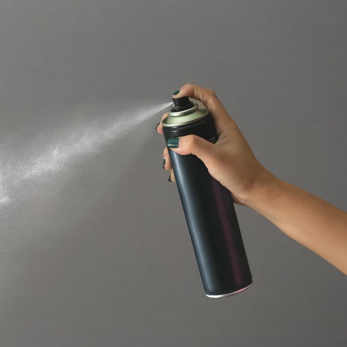 Cropped Hand Of Woman Spraying Against Gray Background