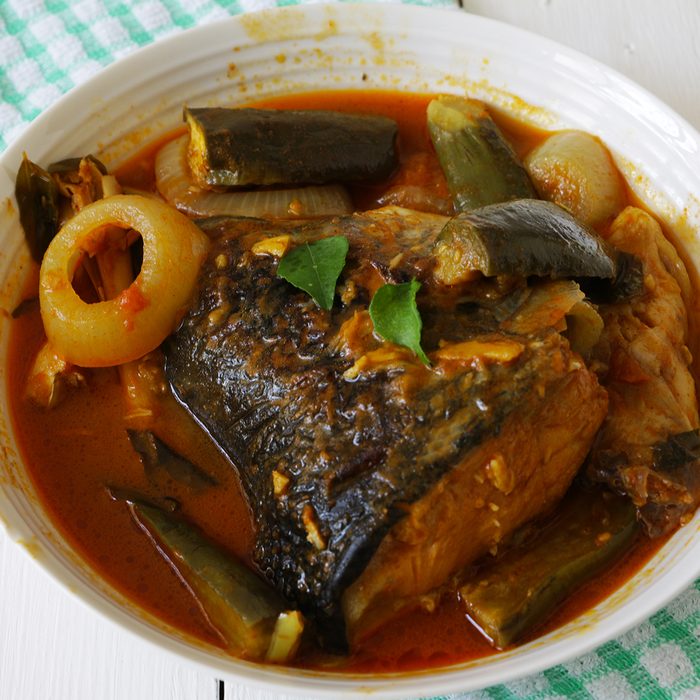indian main dishes Spicy Salmon fish head curry with onion and eggplant on white wooden table