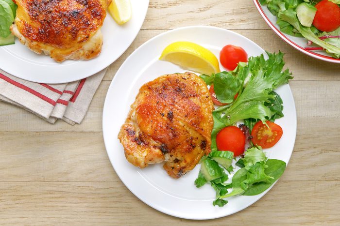 A plate of chicken and salad on a wooden table