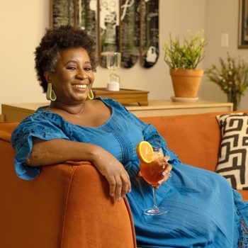 portrait of Nicole A. Taylor on her couch holding a drink
