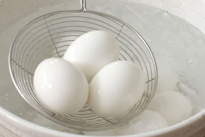 hard-boiled eggs being removed from a pot of water