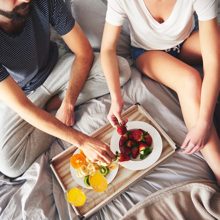 Couple Relaxing On Bed, Eating Strawberries, Elevated View