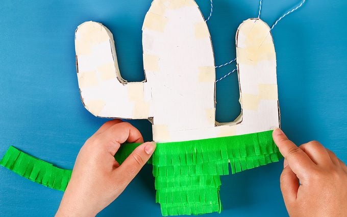 how to make a pinata Diy cinco de mayo Mexican Pinata Cactus made cardboard and crepe paper your own hands on a blue background. Gift idea, decor, game cinco de mayo. Step by step. Top view. Process kid children craft.