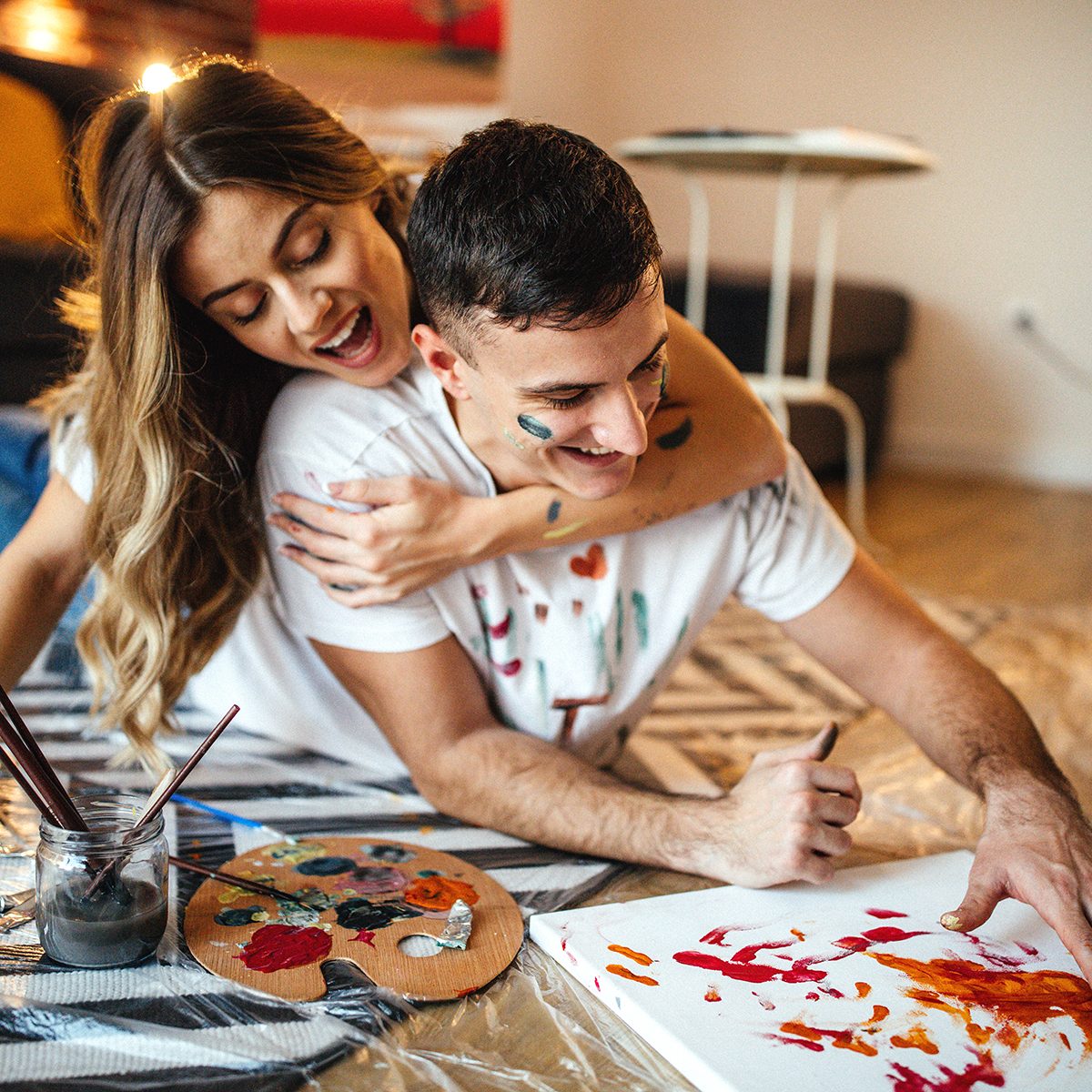 Couple having fun at home, painting on canvas