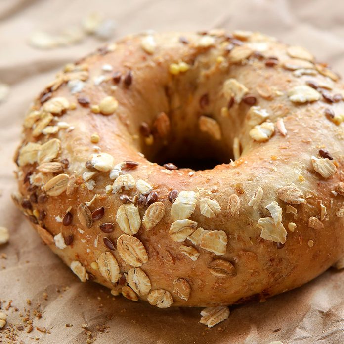 Multigrain bagel covered in oats and seeds on crinkled brown paper