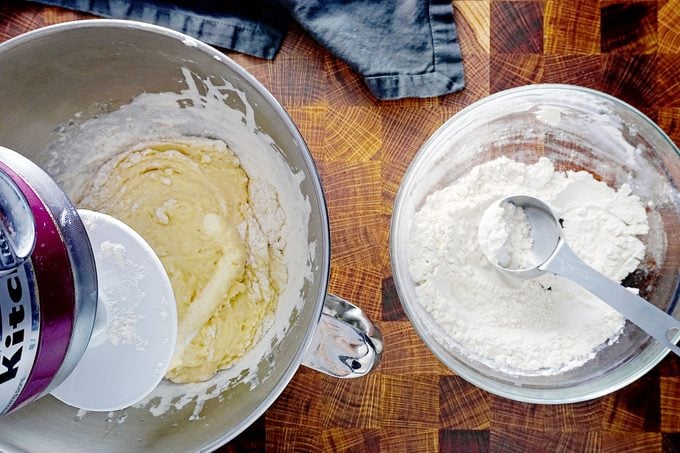 mixing bread stick dough in a stand up mixer with a small glass bowl of flour next to it