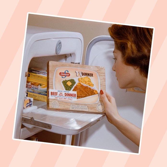 A woman examines a TV dinner box she has taken from the freezer