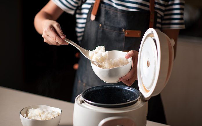 Woman Taking Out And Serving Fresh Boiled Rice From The Cooker