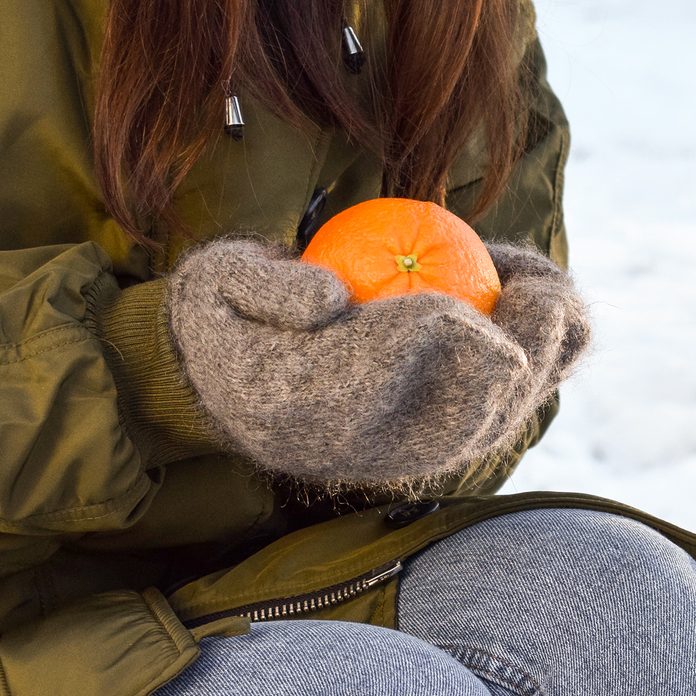Girl with an orange on the background of a winter landscape. easter traditions around the world