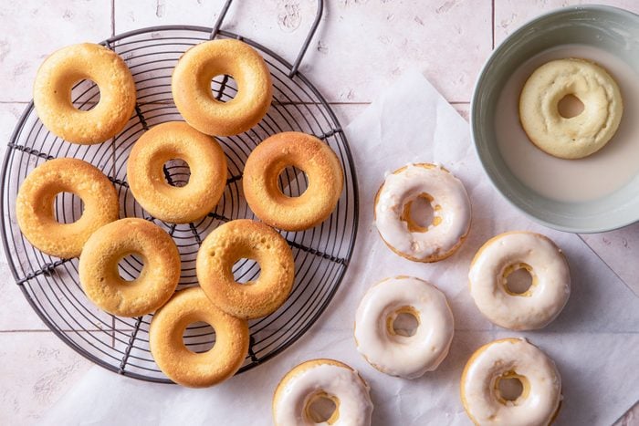 Glazing doughnuts in bowl for Gluten Free Doughnuts