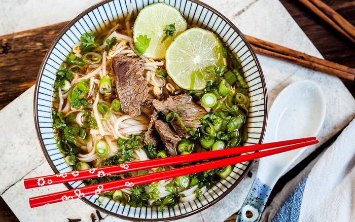 Bowl Of Vietnamese Pho With Rice Noodles, Mung Beans, Cilantro, Spring Onions And Limes