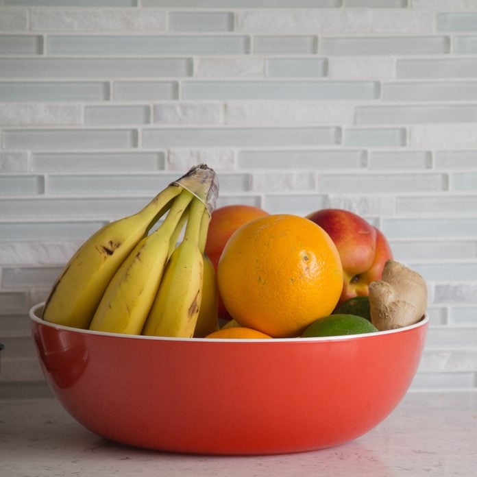 prediabetes foods to avoid Red bowl with fresh fruit on grey granite kitchen counter with glass tile backsplash.