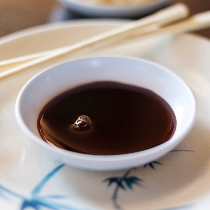 Bowl of soy sauce with chopsticks on table