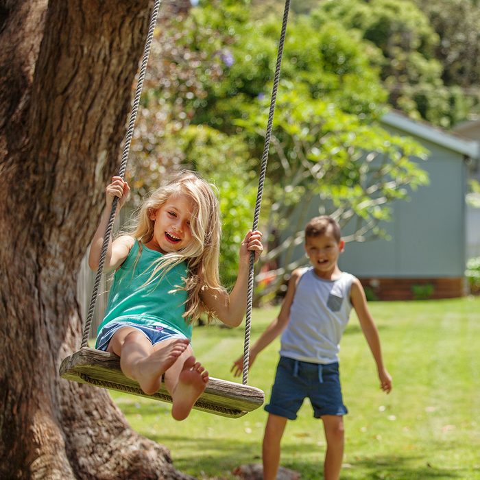 backyard entertainment ideas Brother and sister take turns swinging each other on their tree swing.