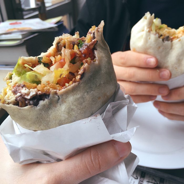 Cropped Hands Holding Burritos At Restaurant