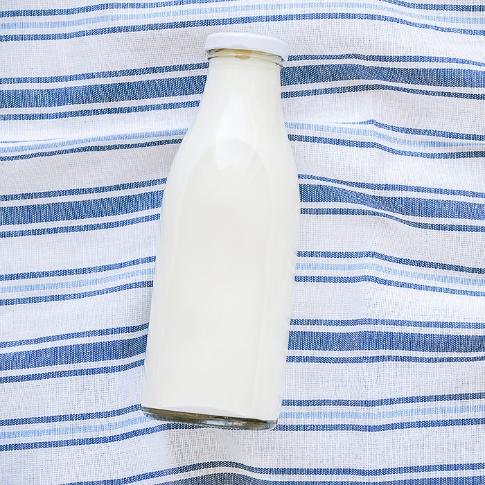 On a striped linen towel is a glass bottle of fresh milk. The concept of healthy organic, farm food. The view from the top. Copy space for text