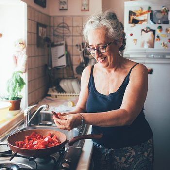 Woman Chopping Tomatoes Into Saucepan Smiling