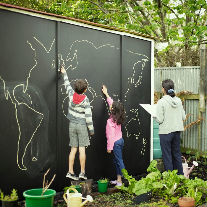 backyard entertainment ideas Mother and children compare atlas picture to world map on garden chalk board.