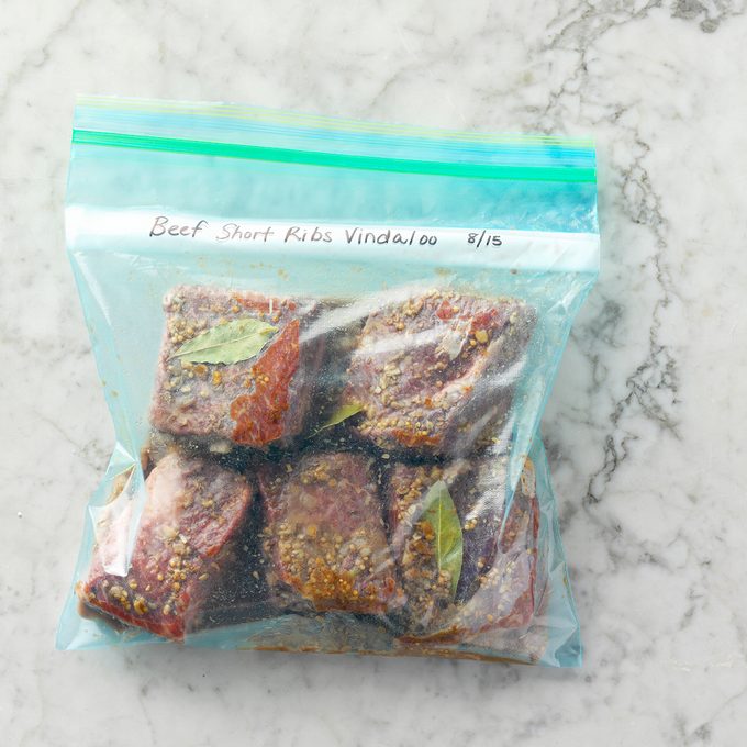 RMS: 132182 Beef Short Ribs Vindaloo Prep Shot, Meal Planner, Food Stylist: Shannon Norris, Set Stylist: Stacey Genaw, prep shot, overhead, gray white marble tabletop, close-up, ziploc plastic bag, beef, cumin seeds, coriander seeds, fresh gingeroot, mustard seed, bay leaves