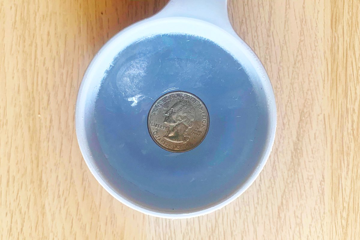 cup with frozen water and quarter showing how to know if your freezer lost power