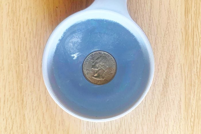 cup with frozen water and quarter showing how to know if your freezer lost power