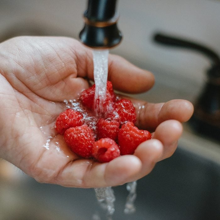 how to wash berries Male Hand Under Running Water To Wash Raspberries