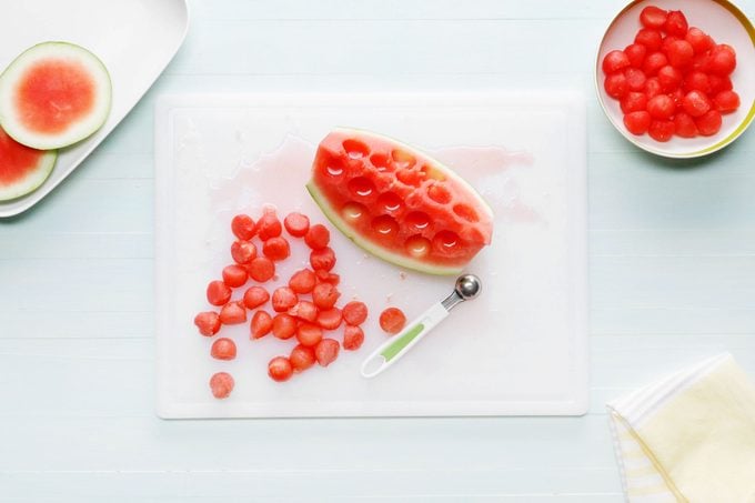 melon balls from a quarter of a watermelon on a white cutting board