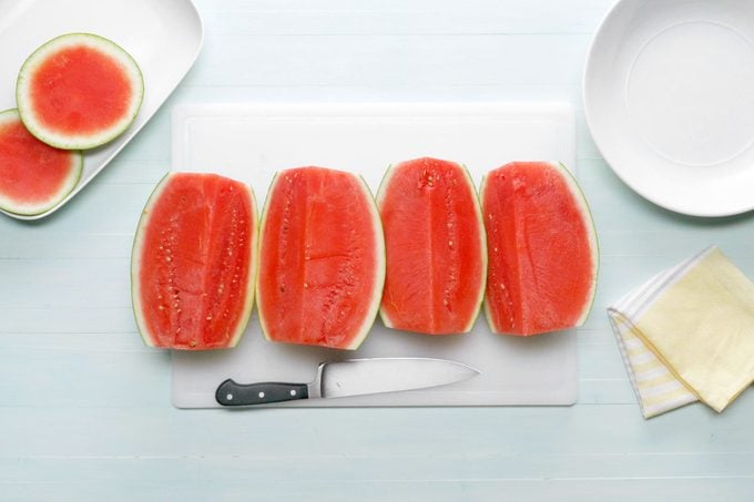 Watermelon quarters on a white cutting board