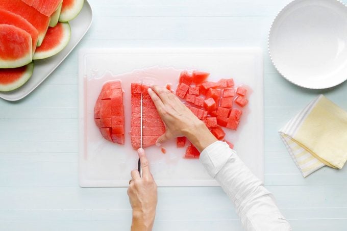 cubing watermelon on a white cutting board