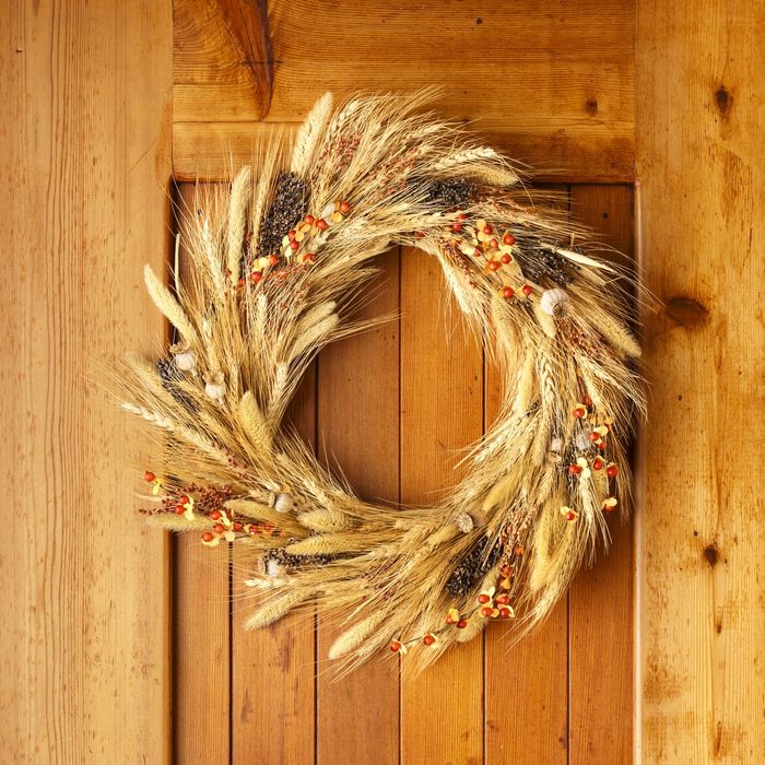 House home front door Fall autumn Thanksgiving decorations country style rustic wreath made of natural botanical materials on wood background