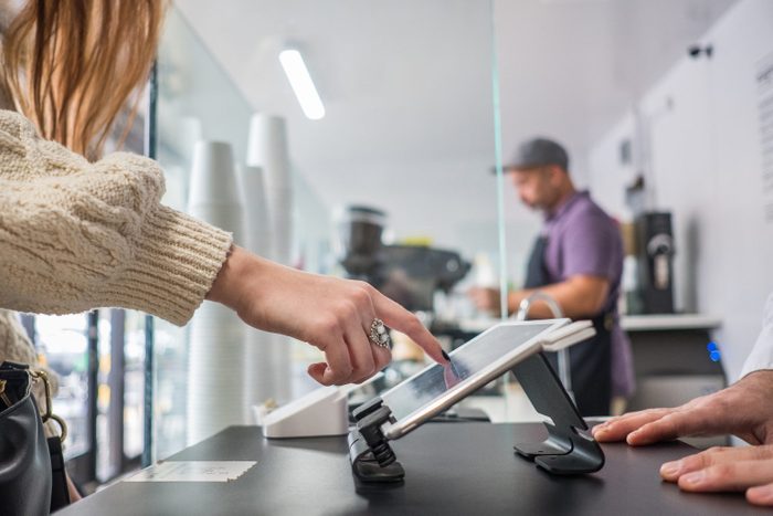 Female Customer Buying Coffee And Placing Signature On Tablet