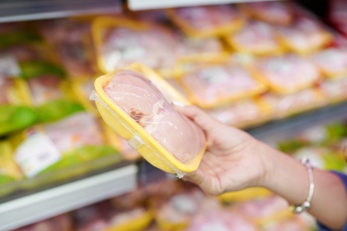 meat in food store . Woman choosing packed fresh chicken meat in supermarket