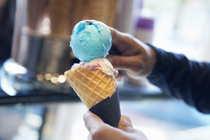 hands scooping blue moon ice cream into a cone in an ice cream shop
