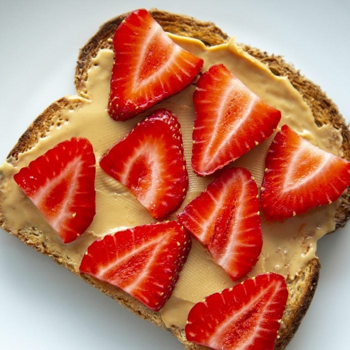 whole grain toast with almond butter and strawberries on a white plate; Healthy Fast Breakfast