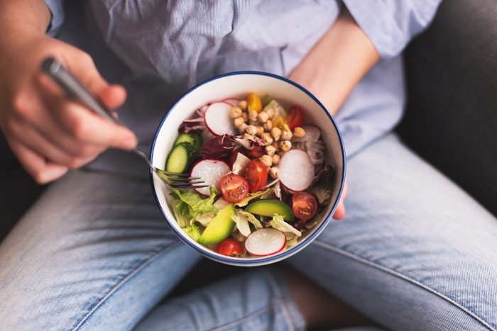 close up of person holding a bowl of healthy salad
