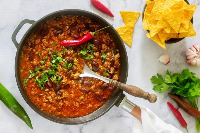 Mexican and American food Chili con carne served with nachos, pepper and herbs.