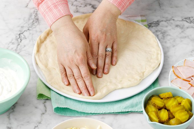 spreading dough out into a pizza pan