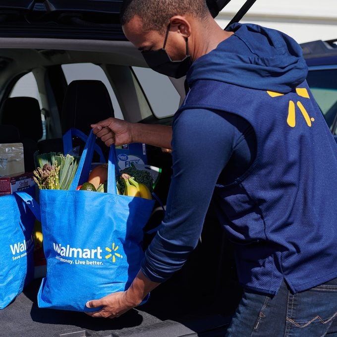 Walmart employee putting groceries in car trunk
