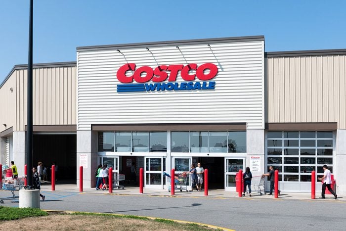 shoppers walk with shopping carts in and out of a Costco entrance on a sunny day in Teterboro, New Jersey