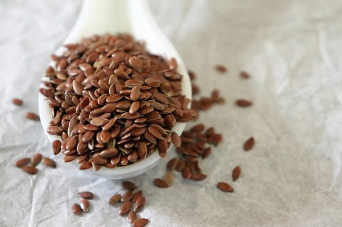 Close-up of flax seeds in a ceramic spoon on white background