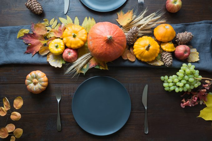 Autumn themed thanksgiving place setting with leaves, garland and pumpkins as decorations