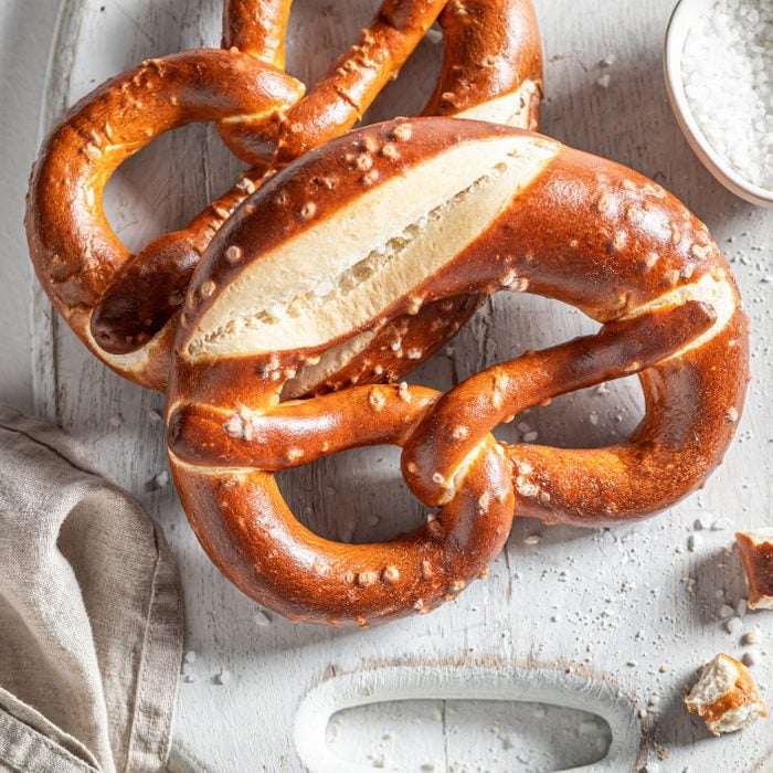 bavarian style pretzels on a white cutting board next to a small dish of salt