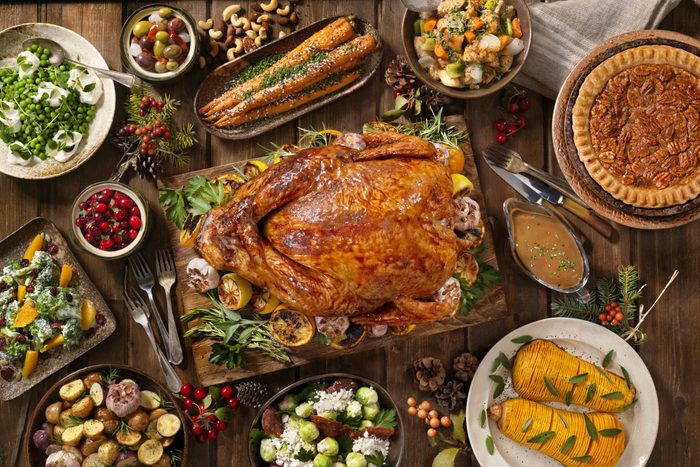 overhead view of thanksgiving dishes around a roasted turkey arranged on a wood table