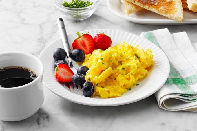 fluffy scrambled eggs with fruit and coffee for breakfast