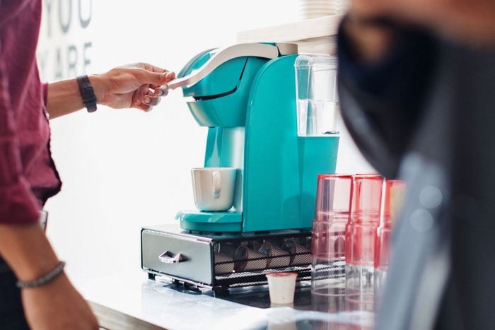 man using a teal Keurig at the office