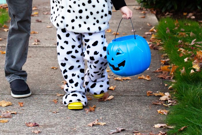child Trick Or Treating with a blue halloween bucket