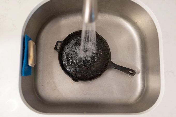 washing cast iron pan in the sink