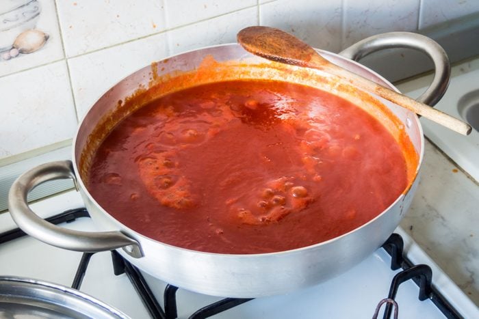 Boiling Tomato Sauce Pot On The Burner With Wooden Spoon