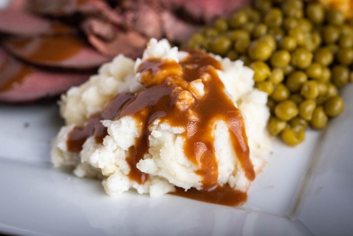 mashed potato serving with gravy sauce on roasted beef platter